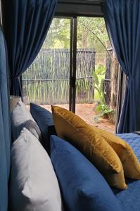 a group of pillows on a bed with blue curtains at Pandora's Guest Lodge in Klerksdorp