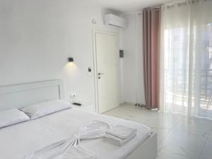 a white bedroom with a white bed with towels on it at Villa Denis Ksamil in Ksamil