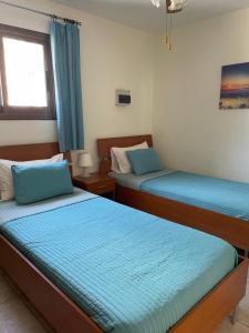 two beds in a room with blue sheets at Villa Kokkinoyia, in Peyia