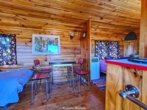 a log cabin bedroom with a bar and stools at Manoir du Bois Joly - Roulotte Vintage in Margon