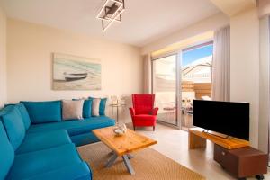 a living room with a blue couch and a tv at Villa Petra Gouvia by Villa Plus in Gouvia