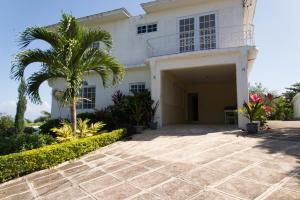 una casa bianca con una palma e un vialetto di Hatfield South Villa a Montego Bay