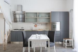 una cocina con armarios grises y una mesa con sillas. en Guest House Sicily, en Siracusa