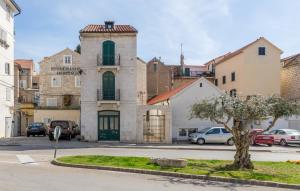 een groot stenen gebouw met auto's geparkeerd op een parkeerplaats bij Stonemasons Heritage in Split