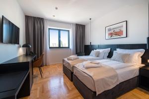 a hotel room with two beds and a desk at Miramare Hotel in Zadar