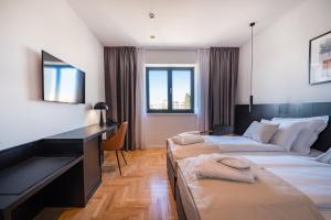 a hotel room with two beds and a desk at Miramare Hotel in Zadar
