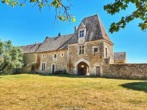 un vecchio edificio in pietra su un prato di Manoir du Bois Joly - Roulotte Vintage a Margon