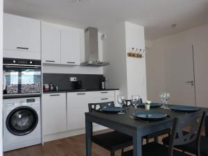 a kitchen with a dining table and a washing machine at L'apaisant in Houlgate
