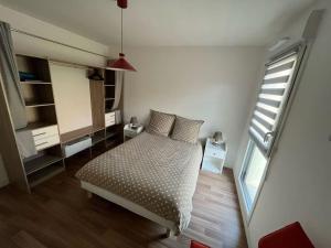 een kleine slaapkamer met een bed en een raam bij L'apaisant in Houlgate