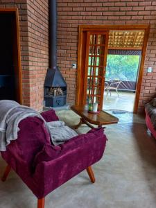a living room with a purple couch and a fireplace at Chalé Araucária- Vale das Pedras MG in Sapucaí-Mirim