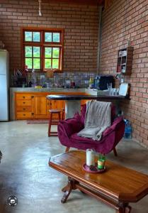 a kitchen with a purple chair and a table at Chalé Araucária- Vale das Pedras MG in Sapucaí-Mirim