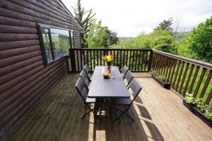 Grove Lodge, Contemporary Cabin in Mendip Hills في أكسبريدج: سطح خشبي عليه طاولة وكراسي