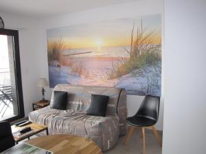 a living room with a couch and a painting of the beach at Bel appartement , à 2km du bassin d'Arcachon in La Teste-de-Buch