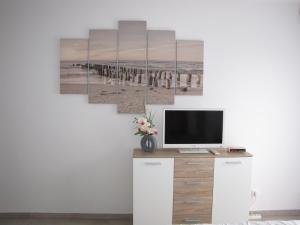 una habitación con TV y una pintura de una playa en Bel appartement , à 2km du bassin d'Arcachon, en La Teste-de-Buch