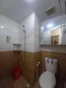 e bagno con servizi igienici e doccia con specchio. di by BELLA PROPERTY Type 2BR Green Pramuka City a Giacarta