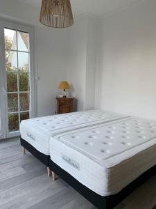 ein weißes Bett in einem Zimmer mit Fenster in der Unterkunft Maison au calme avec jardin près du Château, forêt et plage in Condette