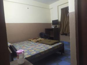 Habitación pequeña con cama y escritorio. en Shree Radha Krishna Guest House By WB Inn en Harchandpur