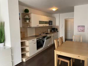 a kitchen with white cabinets and a wooden table at Residenz Sonnenschein in Börgerende-Rethwisch