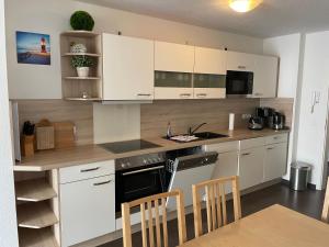 a kitchen with white cabinets and a table and chairs at Residenz Sonnenschein in Börgerende-Rethwisch