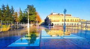 a reflection of a building in a puddle of water at Izo's Home in Kutaisi