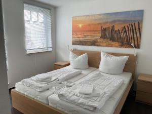 a bed with white sheets and a painting on the wall at Residenz Sonnenschein in Börgerende-Rethwisch