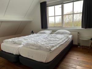 a large bed in a room with a window at Het Landhuis in Oostkapelle