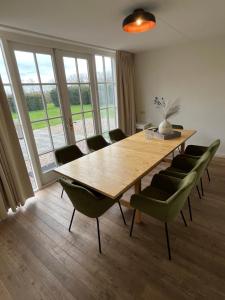uma sala de jantar com uma mesa de madeira e cadeiras em Het Landhuis em Oostkapelle