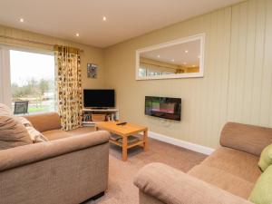 een woonkamer met 2 banken en een tv bij Oak Lodge in Preston