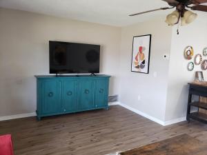a living room with a blue cabinet and a flat screen tv at Shell near the Sea, 2-Br Pet Friendly Home in Venice