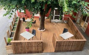 een houten terras met stoelen en een boom bij Logis Hôtel du Fer à Cheval in Yenne