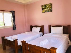 2 camas individuais num quarto com uma janela em โรงแรม เทวาแกรนด์ รีสอร์ท กุฉินารายณ์ กาฬสินธุ์ em Ban Na Ko