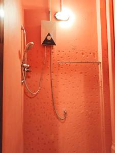 a shower in a bathroom with a red wall at Time Sabai 32 in Bangkok