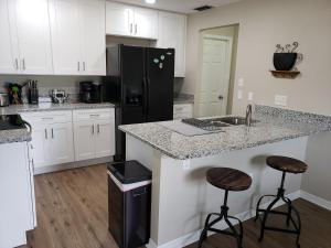 a kitchen with a black refrigerator and two bar stools at Shell near the Sea, 2-Br Pet Friendly Home in Venice