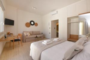 a white bedroom with a bed and a couch at Natal Suite in Ermoupoli