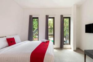 a bedroom with a large bed with a red and white blanket at RedDoorz near Kaza Mall Surabaya in Plosobegem