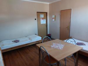een kamer met 2 bedden en een tafel en stoelen bij Penzion Flipper in Revúca