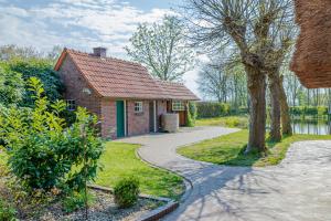 a small brick house with a walkway in front of it at Reetdach Ostfriesenhaus in Südbrookmerland