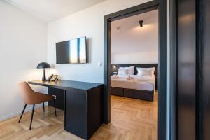 a bedroom with a bed and a desk and a mirror at Miramare Hotel in Zadar