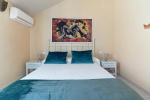 Un dormitorio con una cama con almohadas azules y una pintura en Colina Verde Maspalomas, en Maspalomas