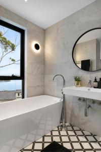 uma casa de banho com uma banheira, um lavatório e um espelho. em Luxury Waterside Home Sanctuary em Sydney