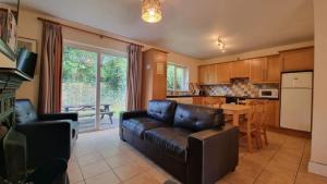 a living room with a leather couch and a kitchen at Kerry Lee Homes in Tralee