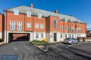 a large brick building with a car parked in front of it at Stay Yorkshire Hamilton Mews Apartment in Doncaster