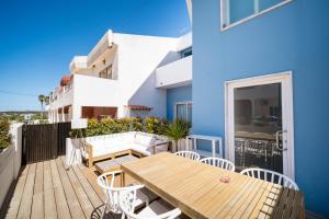 een balkon met een houten tafel en stoelen en een blauw gebouw bij Casa Azul Sagres - Rooms & Apartments in Sagres