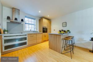 a large kitchen with wooden cabinets and a counter at Stay Yorkshire Hamilton Mews Apartment in Doncaster +4 photos