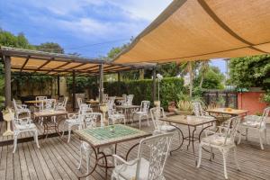 um monte de mesas e cadeiras num deque de madeira em Cap Nègre Hôtel em Le Lavandou