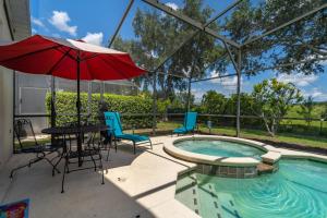 un patio con mesa y sombrilla junto a la piscina en 16813GB Fun in the Sun, en Orlando