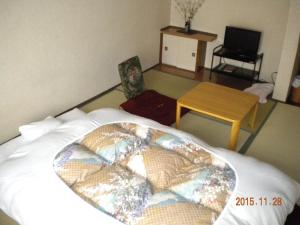 a bedroom with a large bed with a table and a table at Mimatsuso Ryokan in Asahikawa