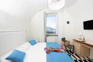 una camera con letto, scrivania e finestra di Le Tre Sirene Luxury House ad Atrani