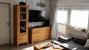ein Wohnzimmer mit einem Entertainment-Center und einem Flachbild-TV in der Unterkunft Ferienwohnung Pittermann in Dornumersiel
