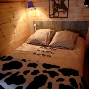 Bett mit Kuhdrucklaken und Kissen in der Unterkunft Le Kota Etable in La Chapelle